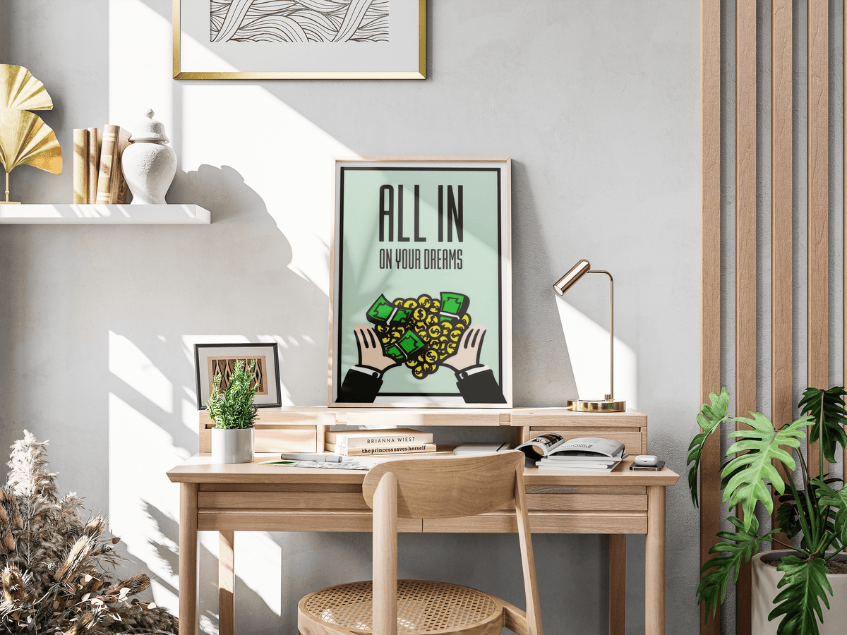 All In On Your Dreams poster standing on a wooden desk beside a brass lamp and books