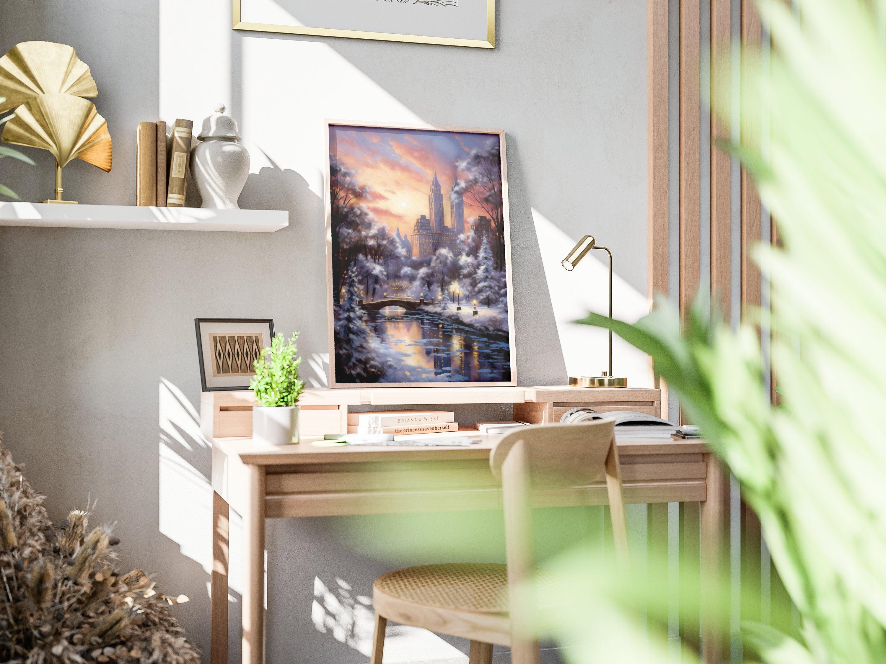 Snowy Central Park sunset print in light wood frame resting on a sunlit wooden desk